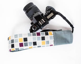 DSLR camera strap cover with lens cap pocket. purple and grey squares.