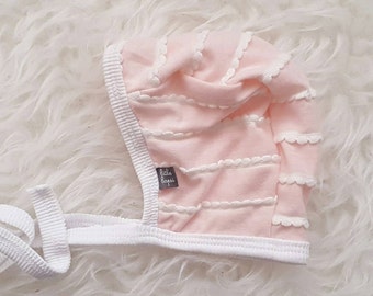 Light pink with white scallop ruffle pilot hat by Little Lapsi. Baby hat with ties.
