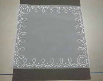 Four squares of white tulle stitched with white designs on the edges