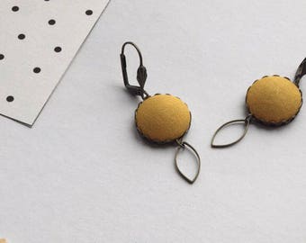 brass earrings and mustard yellow fabric
