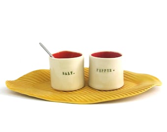 whimsical hand built porcelain salt and pepper cellars sitting on a tray ... red and yellow
