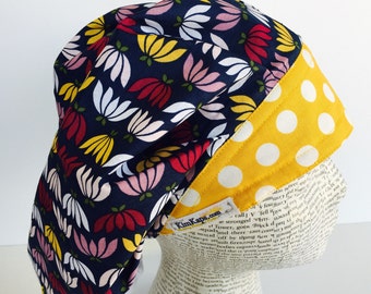 Traditional Bouffant Scrub Cap scrub hat featuring a dark blue material with flowers in pink white and yellow with a coordinating band 2t