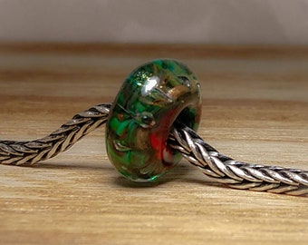 Green and gold with a splash of red. Handmade glass lampwork bead.