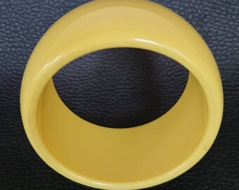 Chunky plastic muted yellow bangle.