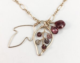 Bracelet or agrémenté de pierres précieuses grenats et saphirs dans un motif de feuilles.