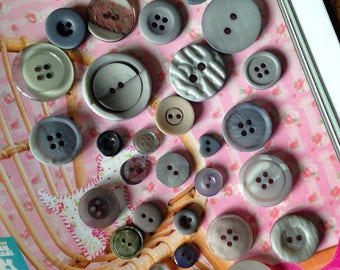 Set of 32 beautiful grey buttons of varying sizes.