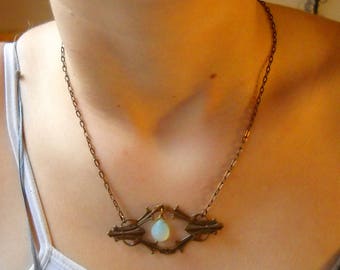 Blue Chalcedony tear drop hangs in the center of a diamond shaped filagree pendant and hangs from a brass chain