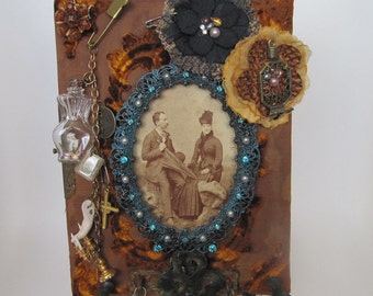 Orange velvet altered album embellished with found objects and mounted on metal frame