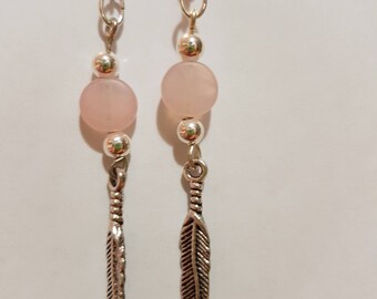 A silver and drop drop earring with feather charm