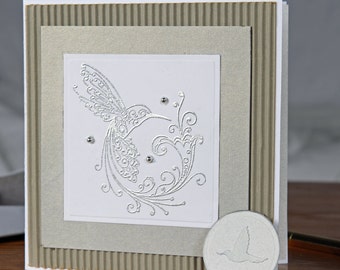 Hummingbird note card. This note card has a delicate silver heat embossed hummingbird and silver balls embellishments.I