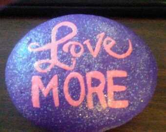Love More in pink paint on rich purple background with sparkles