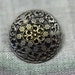 Dark grey metal button with flower pattern