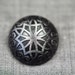Dark grey metal button with geometric motif