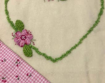 Cream wool blanket with crotchet flowers and hand embroidery. Backed with a cotton patterned fabric.