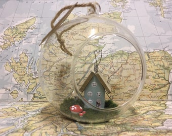 Glass bauble with wooden fairy house and toadstools