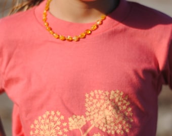 Organic baby T shirt in a pomegranate red, with a light yellow, beautiful fennel flower print. Perfect for any, hip, stylish, baby!