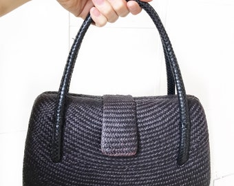 Classic hard shell woven handbag with curved handles.