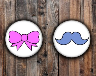 Género revelan pins. Bigote azul y lazo rosa.