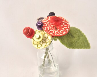 red, purple, and green button flower bottle bouquet