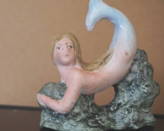 Bisque Mermaid resting on some greenery Figurine