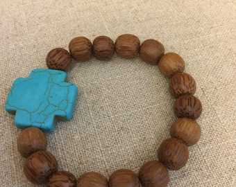 Hand carved wood bead stretch bracelet with turqouise cross accent bead.