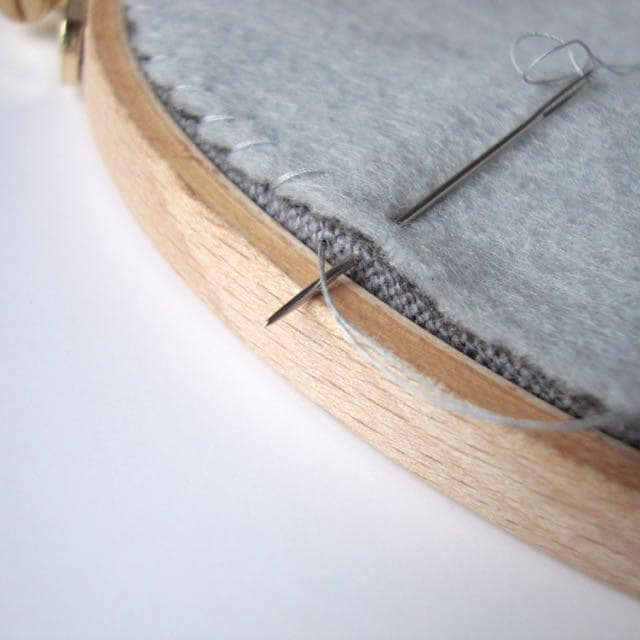 Back your embroidery hoop: whipstitch backing felt in place.