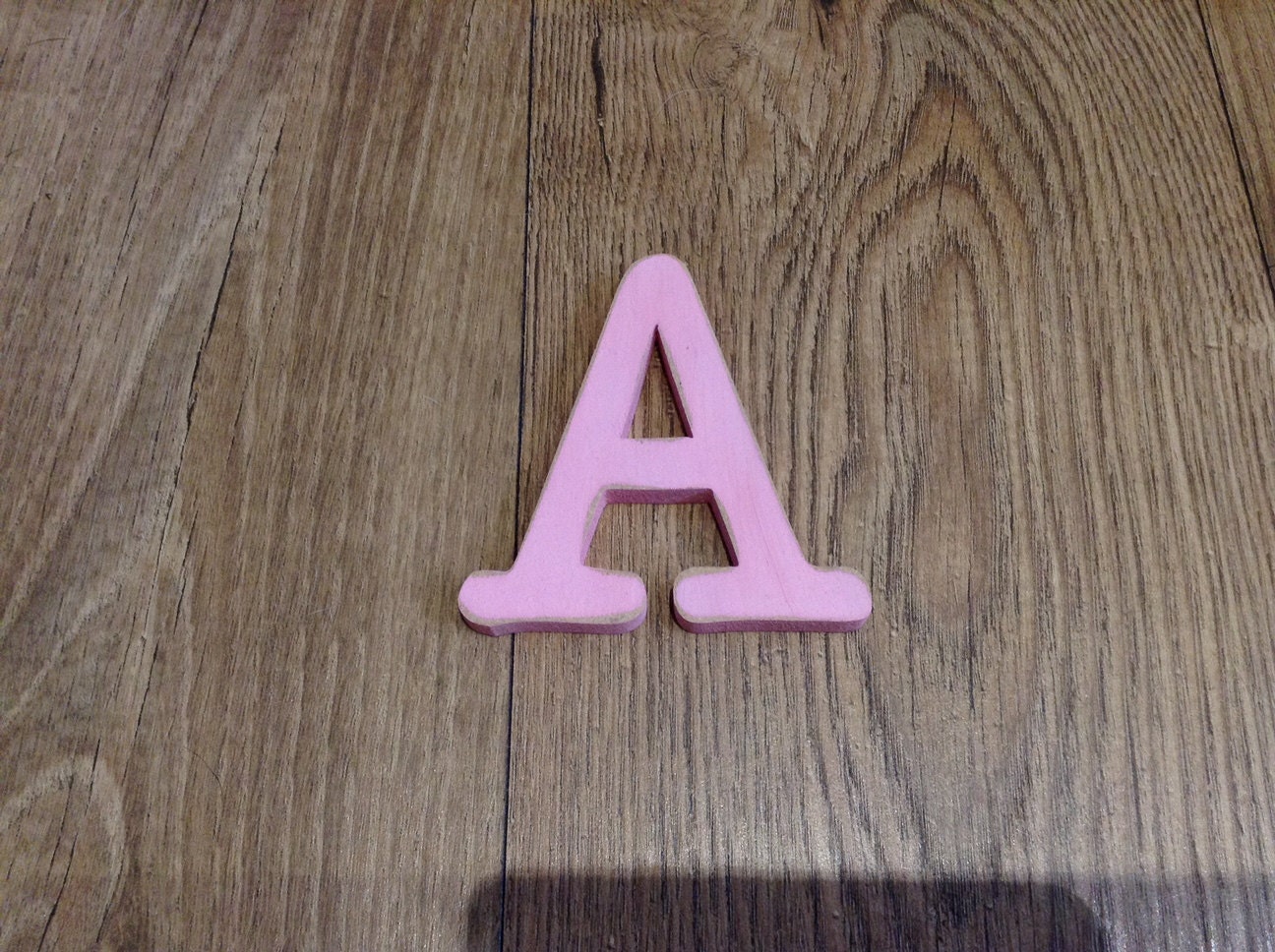 Letter A, in Typewriter font, shown in pink, distressed finish